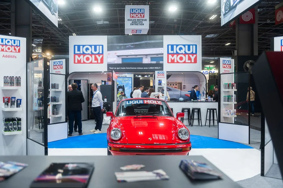 Visiteurs et équipe LIQUI MOLY autour d’une voiture rouge sur le stand.